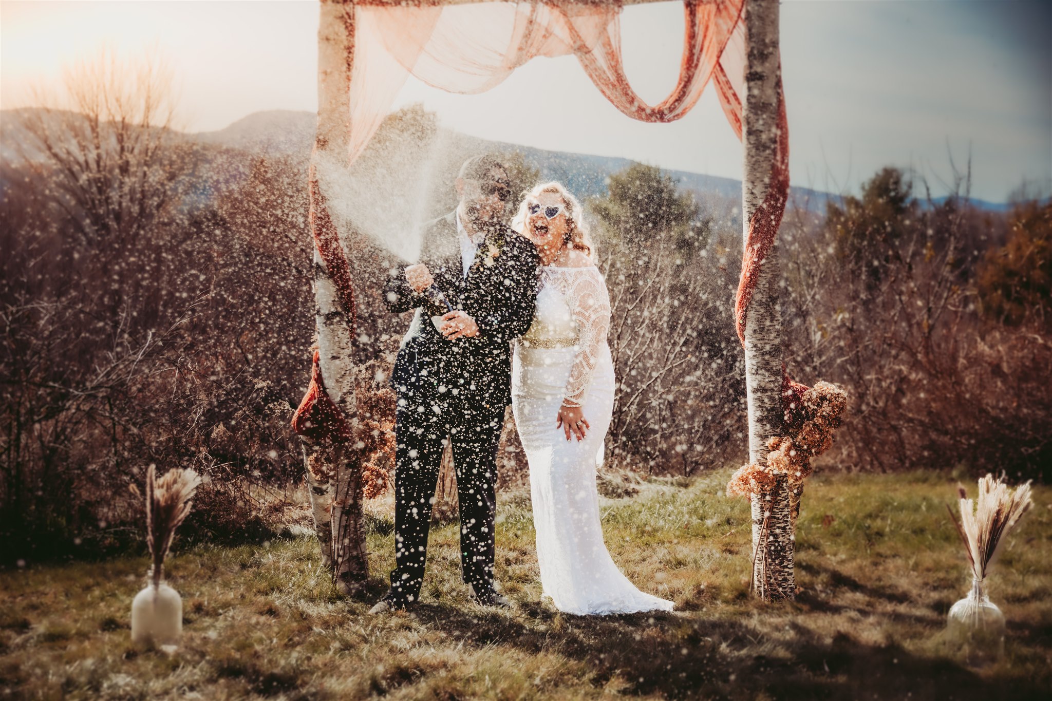 A bride and groom playfully laughing during a champagne pop at their intimate Maine wedding
