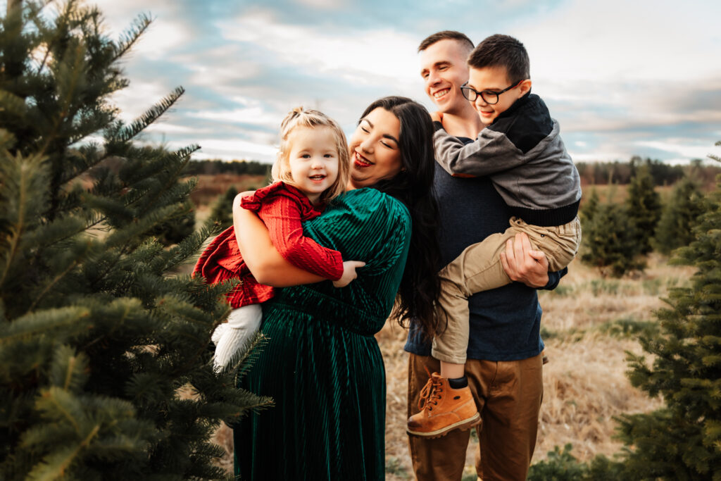 A family standing together among the evergreen trees at a christmas tree farm in Windham, Maine