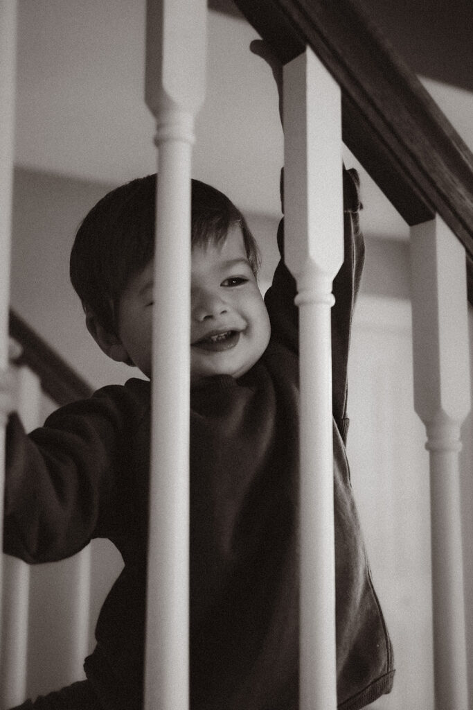 A young boy looks through a railing in his home in Portland, Maine