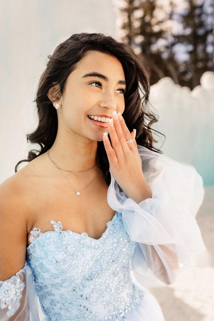 A girl laughs in front of an ice wall at the New Hampshire Ice Castles