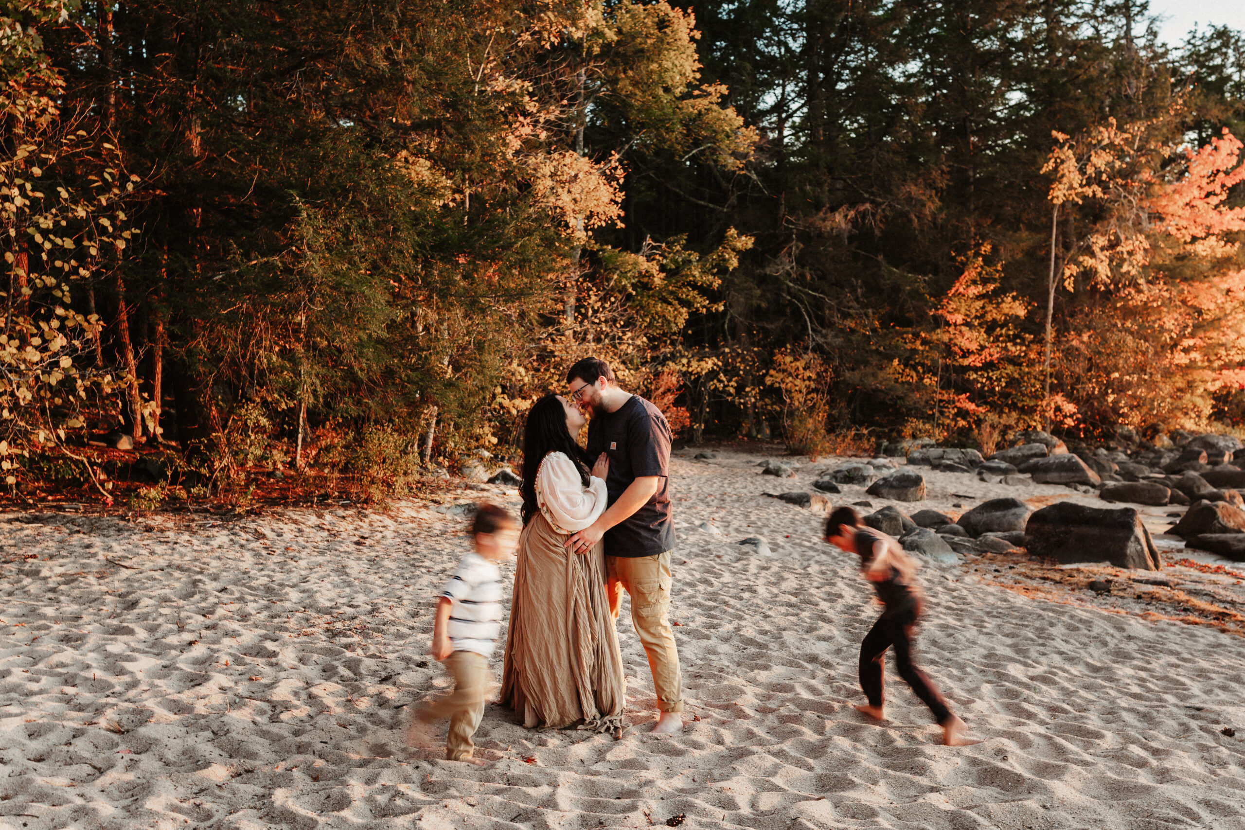 A couple kisses while their children play around them on Sebago Lake