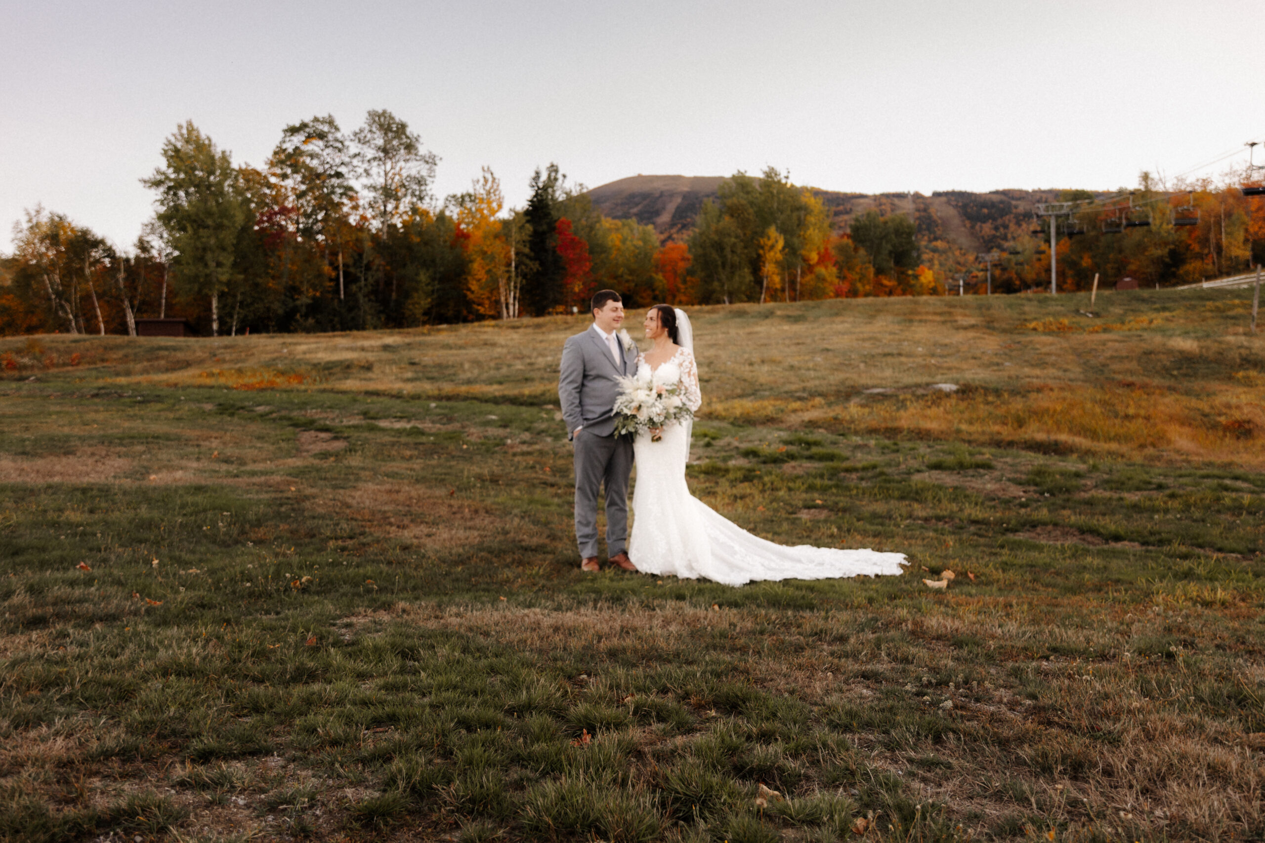 A couple smiles against a colorful fall New England backdrop