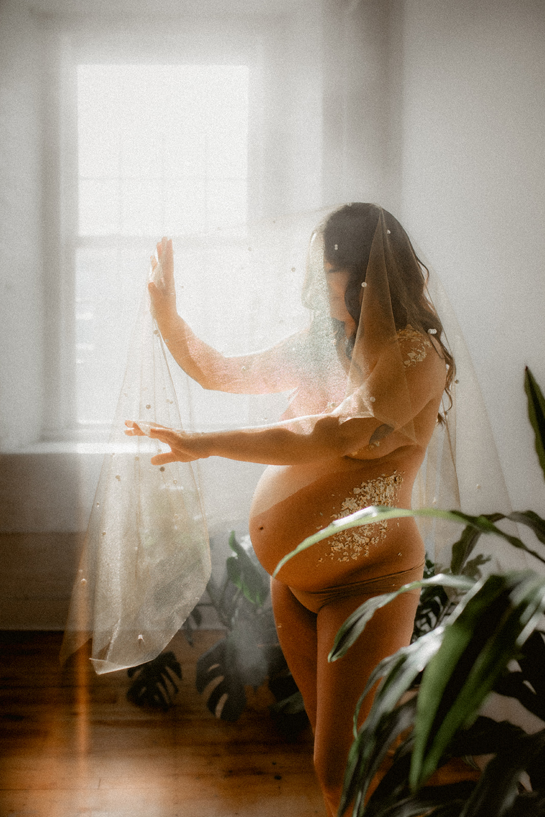 a pregnant woman poses in front of strong sunlight