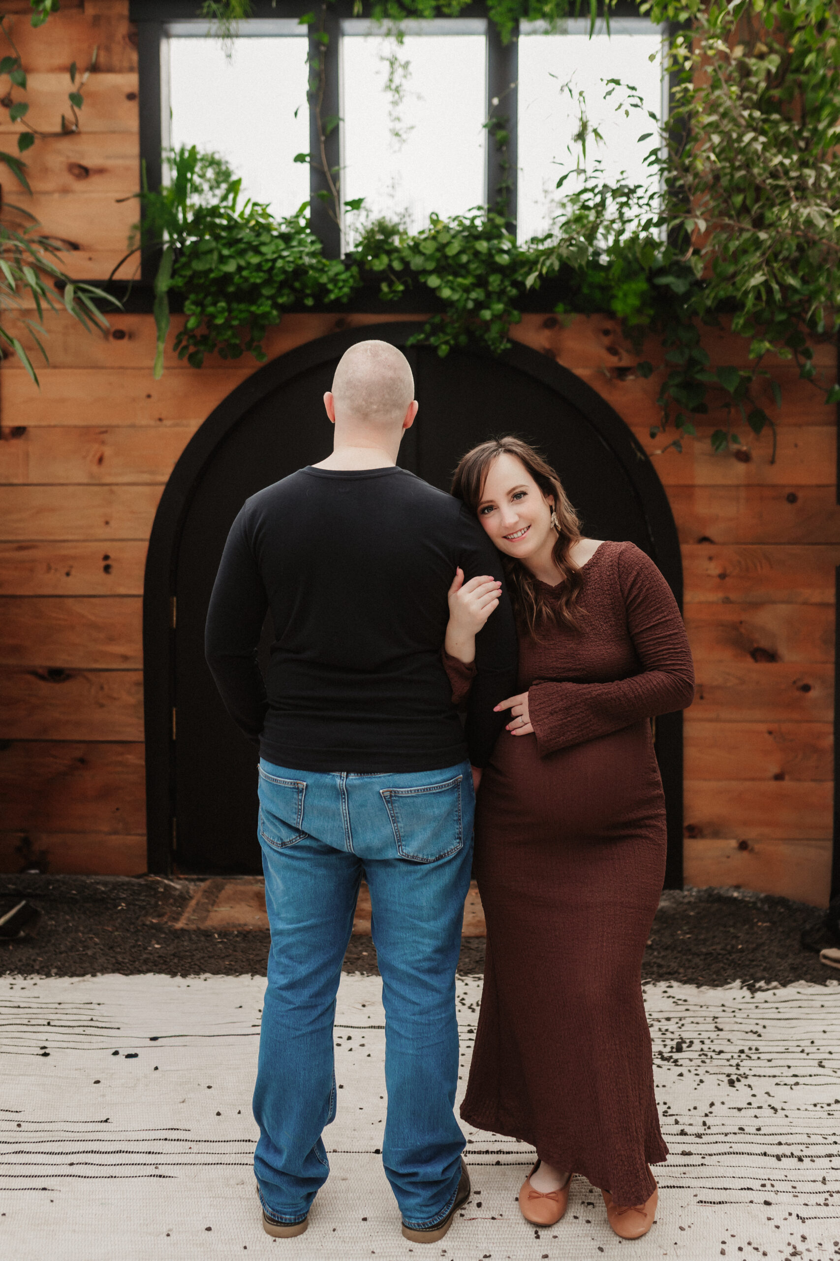 A woman and her husband lean against each other in a custom greenhouse
