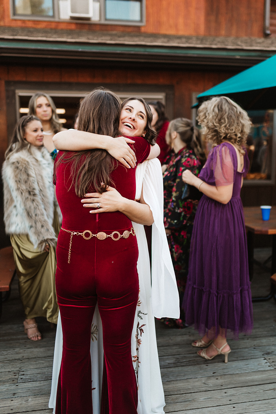 A bride hugs her friend during a reception near Maine Lakeside Cabins
