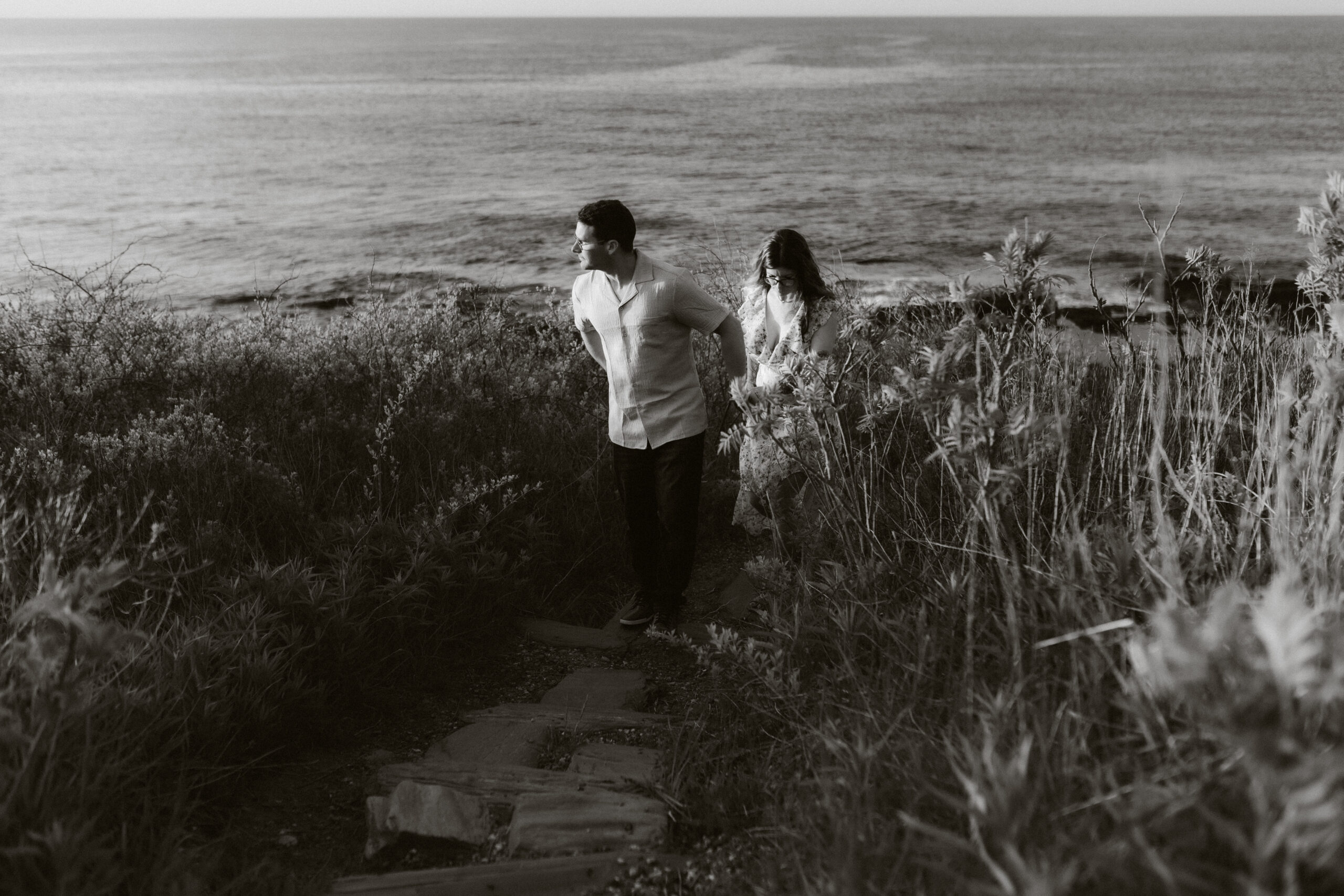 A couple walks along the cliffs of Maine holding hands