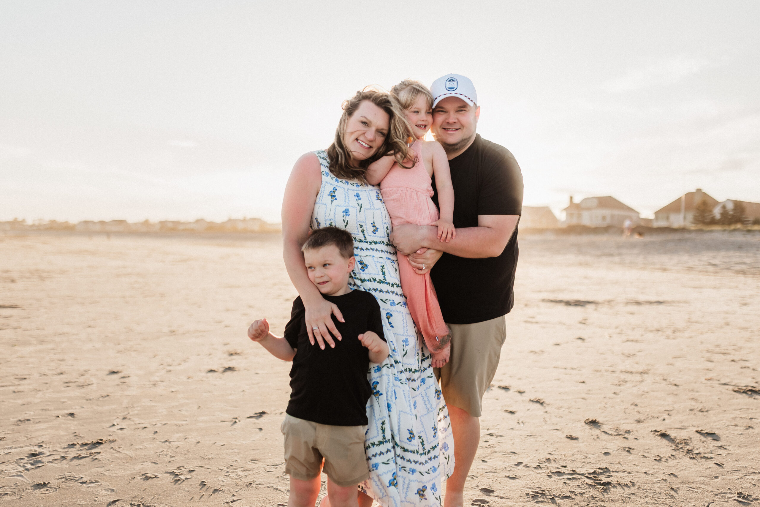 A family embraces each other against the wind on Pine Point Beach